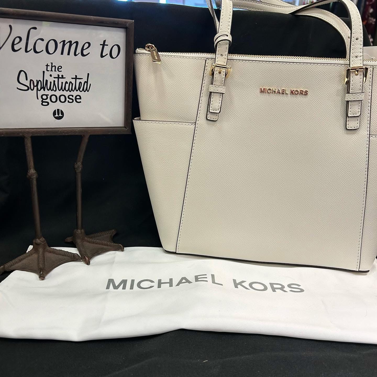 Folding a cashmere sweater beside a designer shopping bag